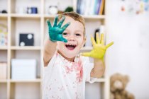 Portrait of smiling little boy showing painted hands — Stock Photo