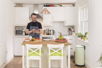 Mann nutzt digitales Tablet bei der Essenszubereitung in der Küche — Stockfoto