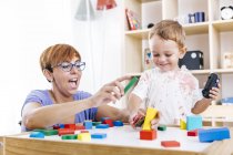 Portrait of little boy and mother playing together with building bricks — Stock Photo