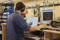Carpenter working with computer in workshop — Stock Photo