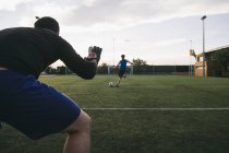 Goleiro preparado para parar a bola com jogador de futebol chutando-o no fundo — Fotografia de Stock