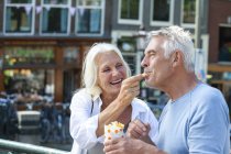 Países Bajos, Amsterdam, feliz pareja de ancianos comiendo papas fritas - foto de stock