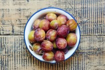 Enamel bowl of plums — Stock Photo