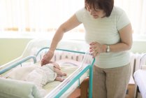 Senior woman watching her newborn granddaughter in a hospital — Stock Photo