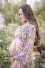 Pregnant woman wearing fashionable bathrobe holding her belly — Stock Photo