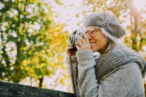 Frau fotografiert mit alter Kamera in einem herbstlichen Park — Stockfoto