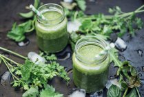 Bicchieri di frullato di erbe selvatiche su superficie scura con ingredienti — Foto stock