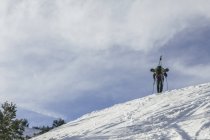 Испания, Человек с лыжами в рюкзаке на вершине снежного холма, гора Пеналара — стоковое фото