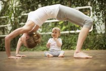 Woman doing yoga exercise while  baby watching her — Stock Photo
