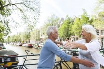 Netherlands, Amsterdam, exuberant senior couple embracing at town canal — Stock Photo