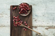 Bowl and spoon with pomegranate seed on wooden tray — Stock Photo