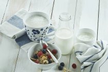 Breakfast with muesli and fruits, cappuchino and bottle of milk — Stock Photo