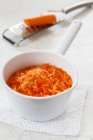 Тертая морковь в кастрюле на белой салфетке — стоковое фото