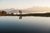 Österreich, altenmarkt-zauchensee, junges paar spazieren am bergsee im niedertauern — Stockfoto