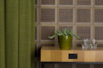 Sideboard mit Gläsern und Topfpflanze vor Holzwandverkleidung — Stockfoto