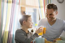Отец и сын вместе завтракают в стаканах с соком — стоковое фото