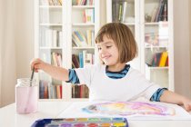 Portrait of smiling girl painting with watercolours — Stock Photo