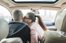 Vista trasera de la mujer besándose hombre en coche — Stock Photo