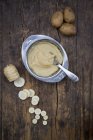 Organic parsnip and potatoes, baby food in bowl and spoon on dark wood — Stock Photo