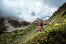 Austria, Altenmarkt-Zauchensee, Basso Tauri, giovane donna felice in piedi in montagna con fiori di campo — Foto stock