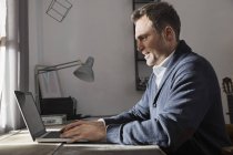 Uomo che lavora con il computer portatile a casa — Foto stock