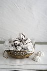 Cuenco de merengues adornados con chocolate en un tazón frente a la pared blanca - foto de stock
