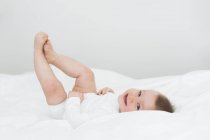 Lächelndes kleines Mädchen liegt auf dem Bett — Stockfoto