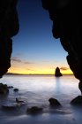 Formazioni rocciose sulla riva dell'oceano al tramonto — Foto stock