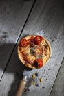 Tomato cheese tart with rosemary on knife over wooden surface — Stock Photo