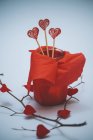 Hearts on wooden sticks in red wrapped jar — Stock Photo