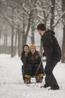 Три друга веселятся с санями зимой — стоковое фото