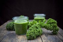Two glasses of kale smoothie on wooden surface — Stock Photo