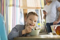 Porträt eines lächelnden Jungen am Frühstückstisch mit Müsli — Stockfoto