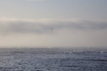 Lighthouse on seashore in fog — Stock Photo