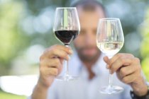 Mann vergleicht Weiß- und Rotwein bei einer Weinprobe — Stockfoto