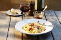 Spaghetti mit Tomatenpesto und geriebenem Parmesan und einem Glas Rotwein — Stockfoto