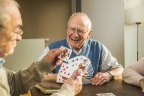 Amici anziani che giocano a carte a casa — Foto stock