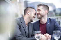 Gay couple sharing an intimate moment at a restaurant — Stock Photo