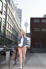 Glückliche blonde Frau mit Fahrrad und Smartphone — Stockfoto