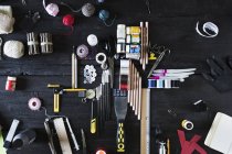 Arrangement von Bastelmaterialien und Werkzeugen auf schwarzem Holz — Stockfoto