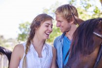 Feliz joven pareja con caballo - foto de stock
