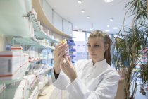 Jeune pharmacien en pharmacie choisir un médicament — Photo de stock