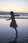 Маленькая девочка на пляже танцует в вечерние сумерки — стоковое фото
