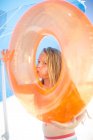 Ragazza sulla spiaggia gonfiare un pneumatico arancione galleggiante — Foto stock