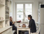 Junge Frau und reifer Mann sitzen in der Küche und frühstücken — Stockfoto