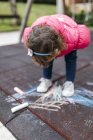 Toddler girl drawing with chalk on ground — Stock Photo