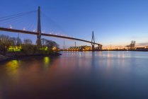 Germania, Amburgo, vista sul porto e sul ponte Koehlbrand illuminato al crepuscolo — Foto stock
