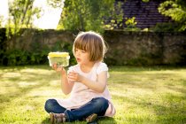 Menina com lata de inseto sentado em um prado — Fotografia de Stock