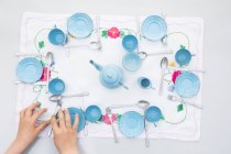 Girl playing with old light blue enamel doll china set — Stock Photo