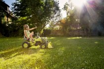 Девочка играет с игрушечным трактором в саду — стоковое фото